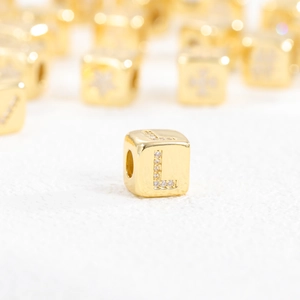 Macro detail of 18k gold plated cube bead with sparkling cubic zirconia letter L charm