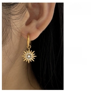 Detailed view of gold plated sunflower earrings with cubic zirconia on a female model