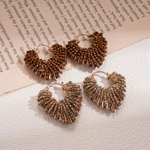 Vintage heart-shaped glass bead hoop earrings in brown and iridescent colors on newspaper