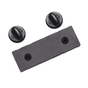 Detailed macro view of matte black metal brooch base with dual pins and rubber clutches
