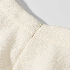Dettaglio ravvicinato del tessuto in tweed bianco e della cerniera invisibile sulla gonna