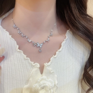 Detailed view of a silver butterfly pendant necklace with zircon on a model neck