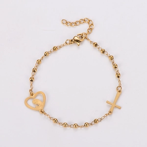 Close-up of golden beaded bracelet with heart-shaped Virgin Mary and cross charms