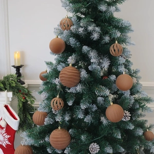 Brown velvet Christmas ball set on frosted pine branch with warm fireplace background