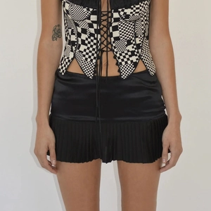 Women's chic black and white checkered corset vest with black pleated satin mini skirt