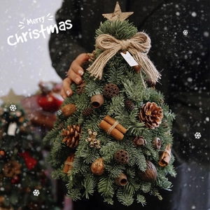 Miniature handmade Christmas tree with pine cones and cinnamon on a wooden base