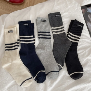 Striped cotton crew socks set in five colors laid out on a white fabric background