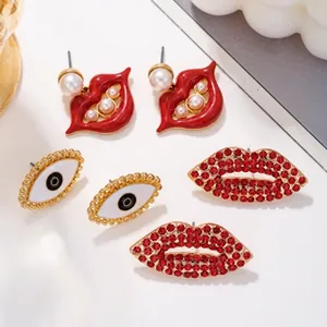 Detail trendiger Goldohrringe mit roten Lippen mit Perlen und Teufelsaugen-Designs