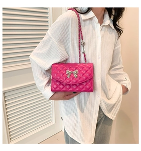 Detail of rose pink quilted crossbody bag with silver bow accent and chain strap