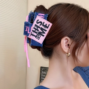 Close-up of denim fabric hair claw clip with pink bow and THIS IS ME embroidery on hair