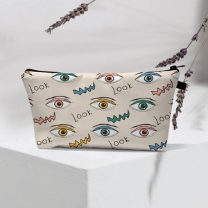 Detail of canvas evil eye makeup bag with Look text on a white geometric stand