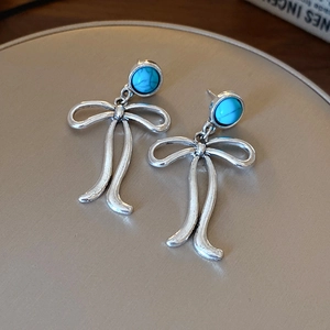 Gros plan de boucles d'oreilles nœuds en argent vintage avec pierres turquoise bleues