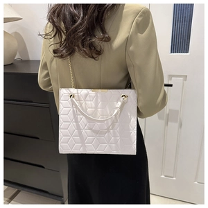 Detail of white quilted handbag with golden chain strap and geometric patterns on a model