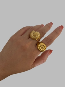 Detailed view of vintage gold hollow seashell and spiral rings worn on fingers