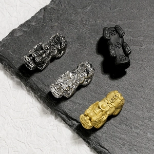 Macro detail of solid 304 stainless steel Pixiu charms in four metallic finishes