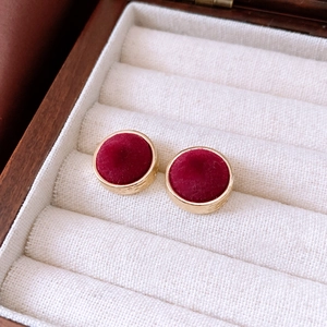 Detailaufnahme der runden Goldohrringe mit rotem Samt-Inlay im Retro-Stil und edlem Metallrand