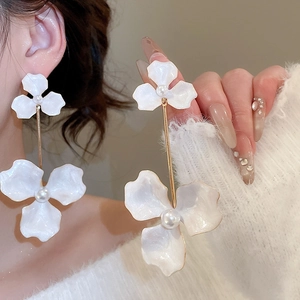 Close-up of white layered flower drop earrings with pearls and gold edges on model