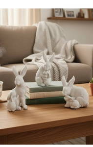 Détail de trois figurines de lapins mère et enfant en résine sur une table en bois