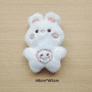 Detail of white plush rabbit accessory with pink embroidery, measuring 8cm by 5cm