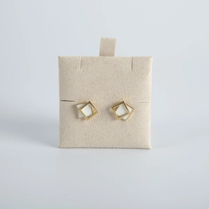 Detailed close-up of geometric square earrings on a beige velvet jewelry card insert