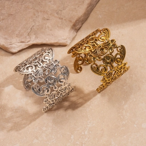 Lace-style hollow floral open cuff bracelets in gold and silver finishes on stone background