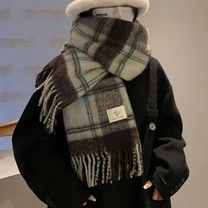 Detail of plaid scarf with fringe in brown and blue colors worn by model in street style