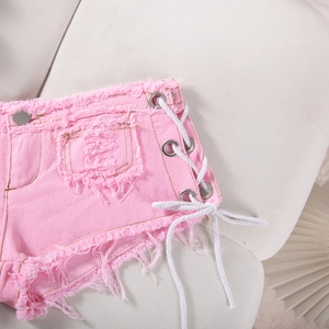 Dettaglio degli shorts in denim rosa con lacci laterali bianchi e bordi sfrangiati grezzi