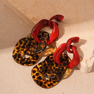 Detail of red acrylic chain links with leopard print rings on a textured stone surface