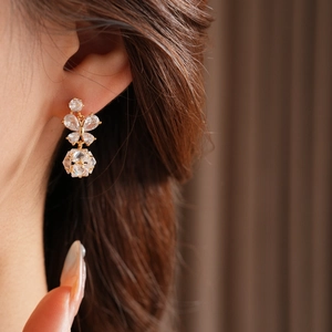 Gros plan de boucles d'oreilles papillon dorées avec zircons portées par un mannequin