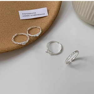 Detail of silver twist stackable open rings showing heart and bow designs
