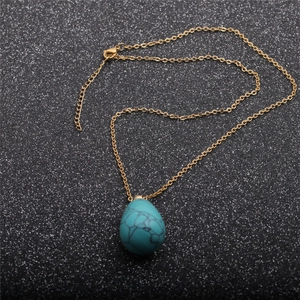 Détail du pendentif flacon de parfum en pierre bleue en forme de goutte et chaîne dorée