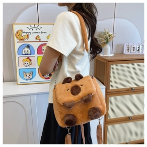 Brown Capybara plush shoulder bag with metal chain shown on a model in a cozy room