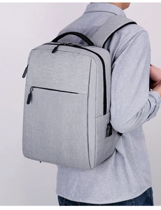 Detail of grey fabric laptop backpack featuring built-in USB charging port and black zipper