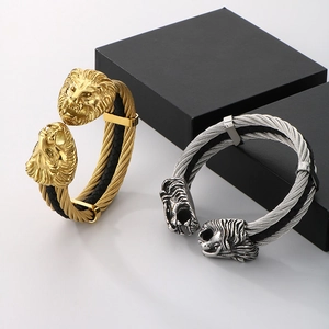 Dettaglio dei bracciali a cavo con testa di leone in oro e argento e trama metallica