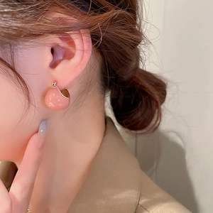 Close-up of pink round bead drop earrings with gold plated geometric ear clips on a model