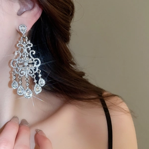 Detailed close-up of long silver chandelier earrings with flower and teardrop pendants
