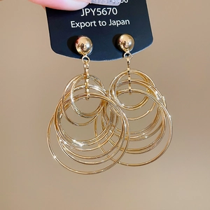 Detail of layered gold metal hoop earrings displayed on a black export card
