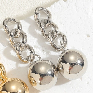 Dettaglio macro di sfere di metallo lucido su orecchini a catena in oro e argento