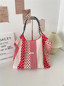 Detail of red and white polka dot canvas tote bag with woven checkerboard handle