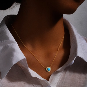 Close-up of golden necklace with a blue heart turquoise pendant on a female neck