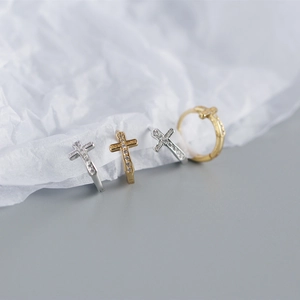 Detailed close-up of gold and silver cross stud earrings with sparkling rhinestones