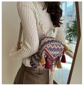 Close-up of bohemian woven mini backpack with colorful fringe details on a female model