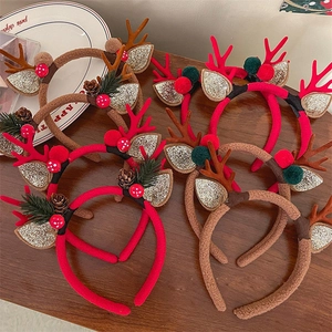 Detail view of plush Christmas reindeer antler headbands with pine cones and berries
