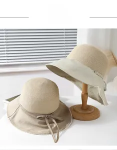 Detail of straw bucket hat with wide cotton brim, lace edges, and decorative bow tie