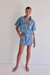 Detail of light blue denim cargo two-piece set with short sleeve top and mini skirt
