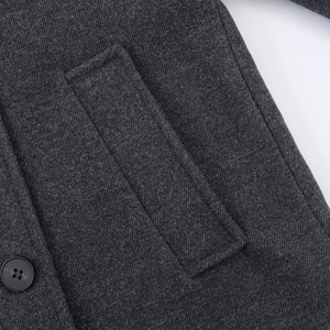 Close-up detail of dark grey wool coat featuring twill texture and black button