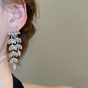 Close-up of elegant flower leaf crystal tassel drop earrings worn by a model