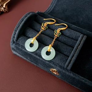 Vue macro de boucles d'oreilles papillon en or 18K avec pendentifs anneaux vert clair
