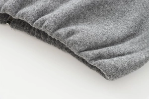 Macro detail of charcoal grey fleece jacket fabric with ribbed elastic cuff and metal zipper
