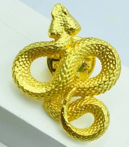 Macro shot of gold snake brooch showing detailed scale texture and butterfly clasp back
